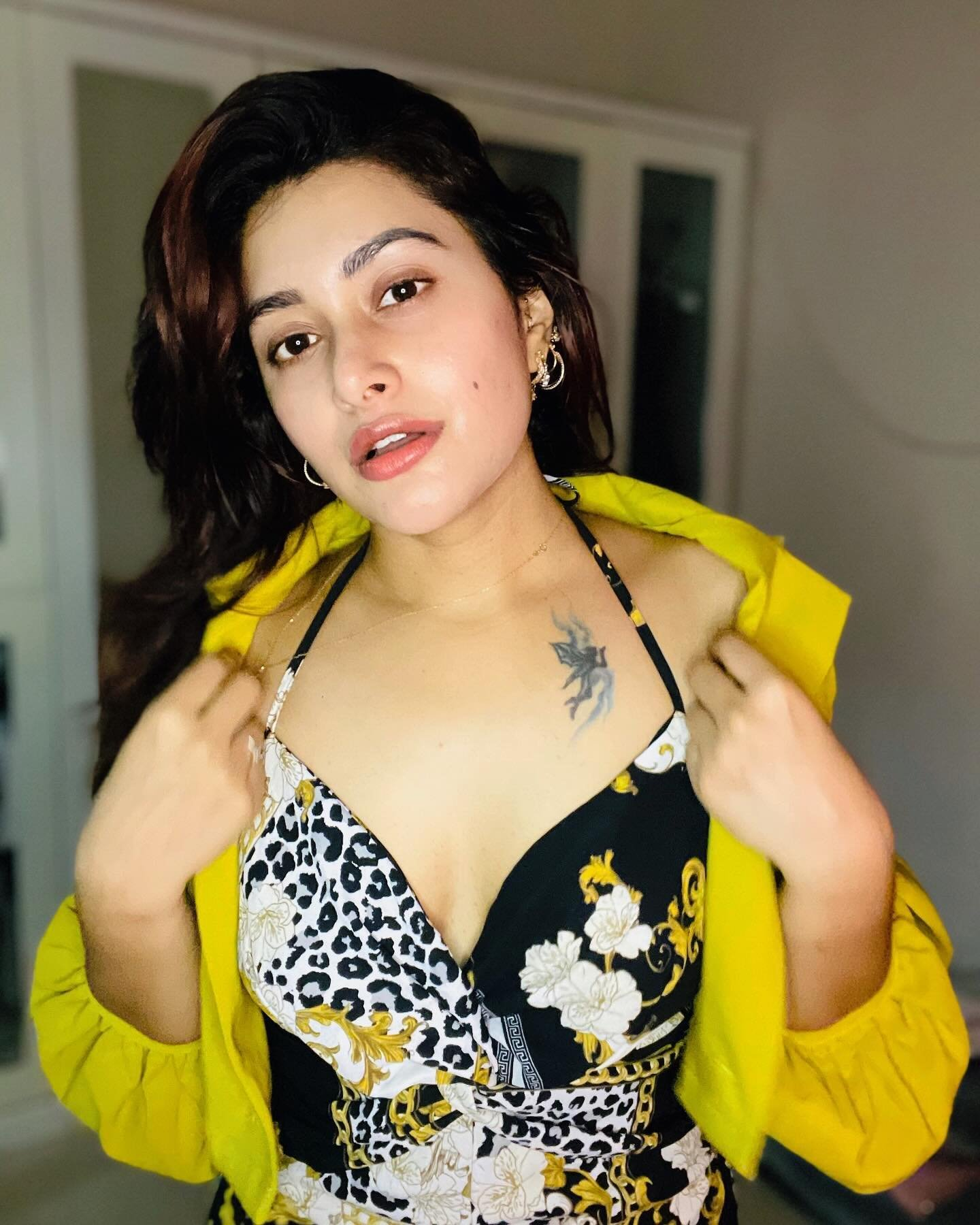 Woman in patterned dress and yellow jacket.