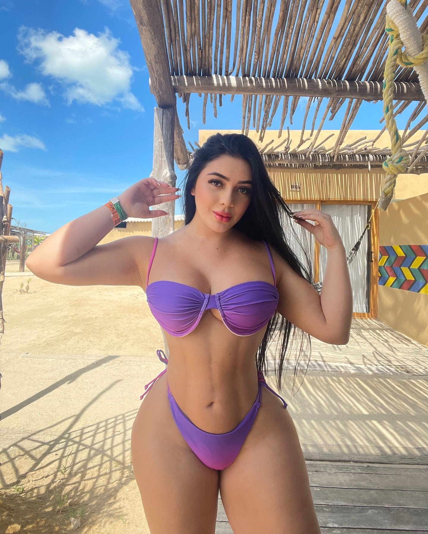 Woman in purple bikini posing outdoors.